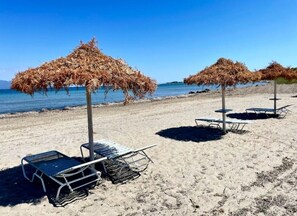 Una spiaggia con lettini e ombrelloni di paglia.