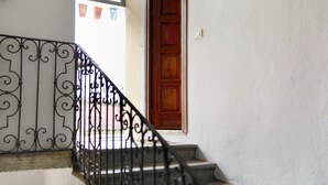 Un escalier orné de rampes en métal travaillées, menant à une porte en bois.