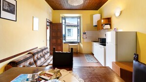 Un salon confortable avec un canapé, une table à manger avec des magazines, et un coin cuisine équipé d’un réfrigérateur et d’un four à micro-ondes.