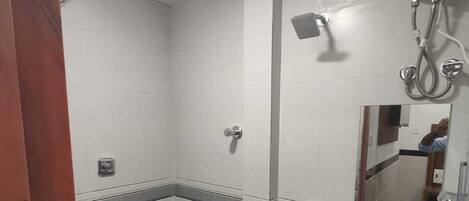 A bathroom with a toilet, a sink, a shower, and a bucket.