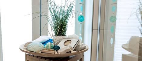 A wooden table with a tray holding a plant, a book, and a towel.