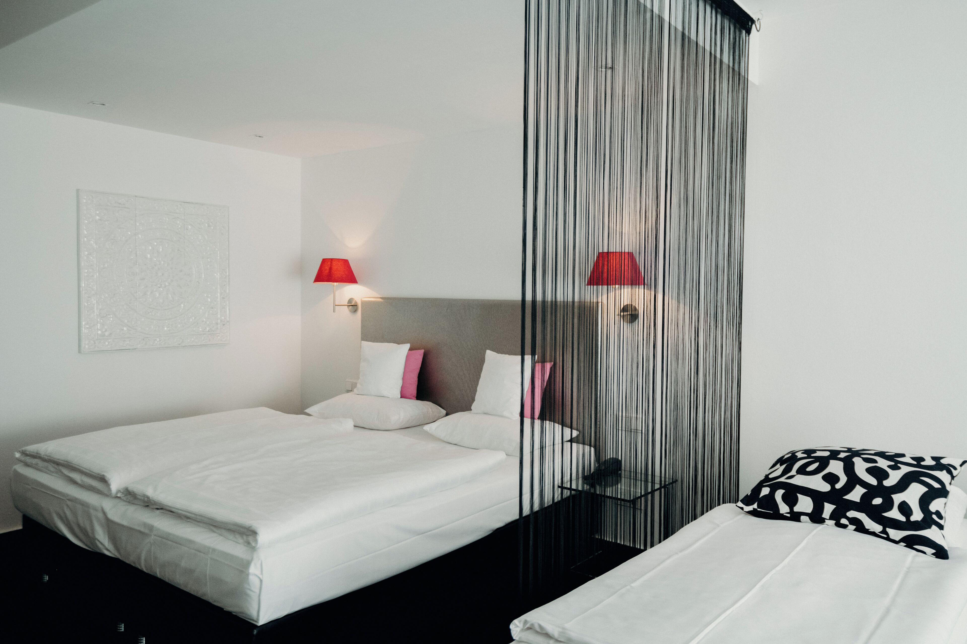 Una habitación de hotel moderna con una cama grande, una mesita de noche, una silla y un separador de cortinas.