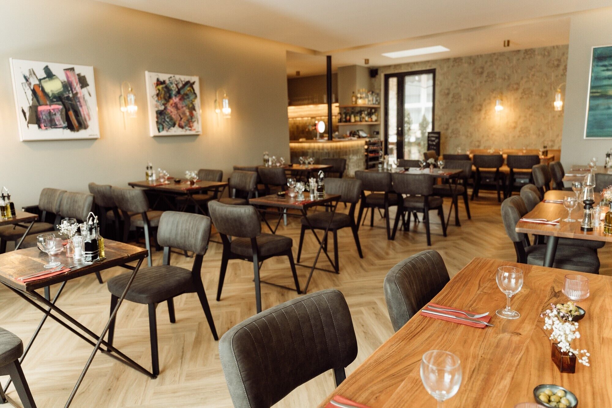 Ein Restaurant mit mehreren Tischen, Stühlen, einer Bar und Kunstwerken an den Wänden.