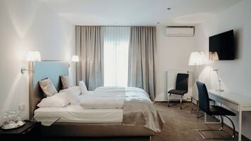 A hotel room with a bed, desk, chair, and curtains.