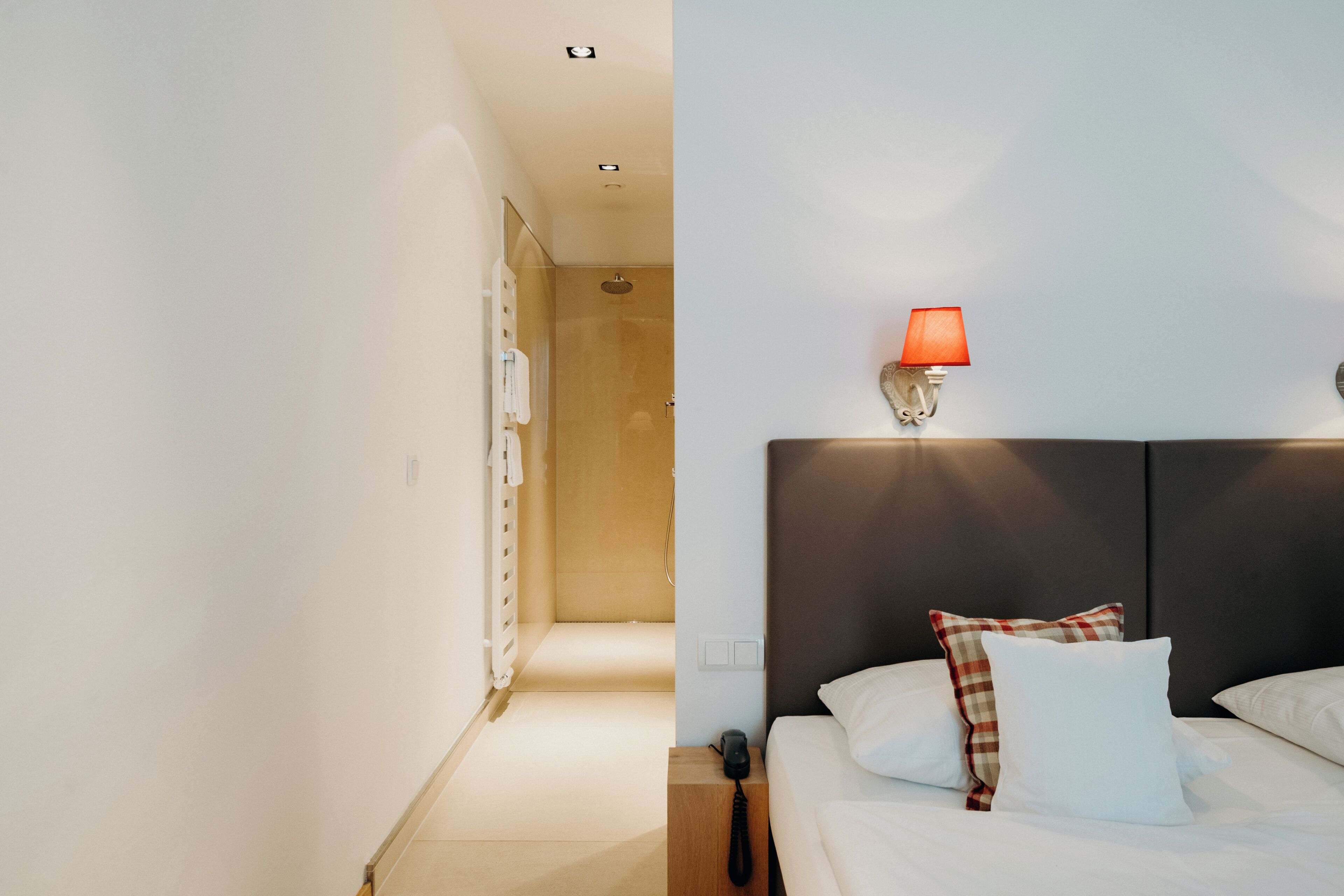 Une chambre d’hôtel avec un lit, une table de chevet, une lampe et un espace douche.
