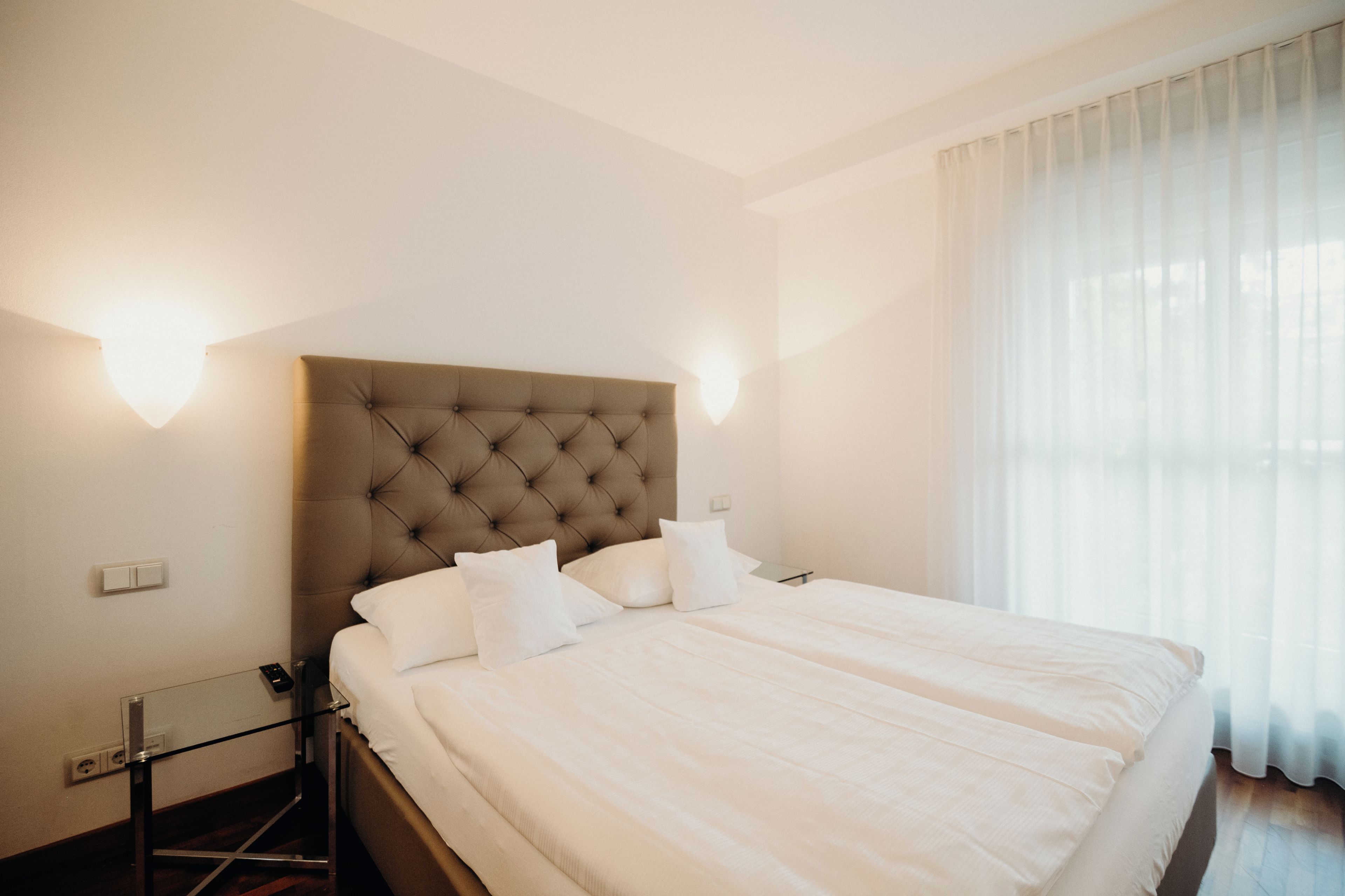 Quarto de hotel com uma cama grande, uma mesa de cabeceira e uma mesinha de apoio.