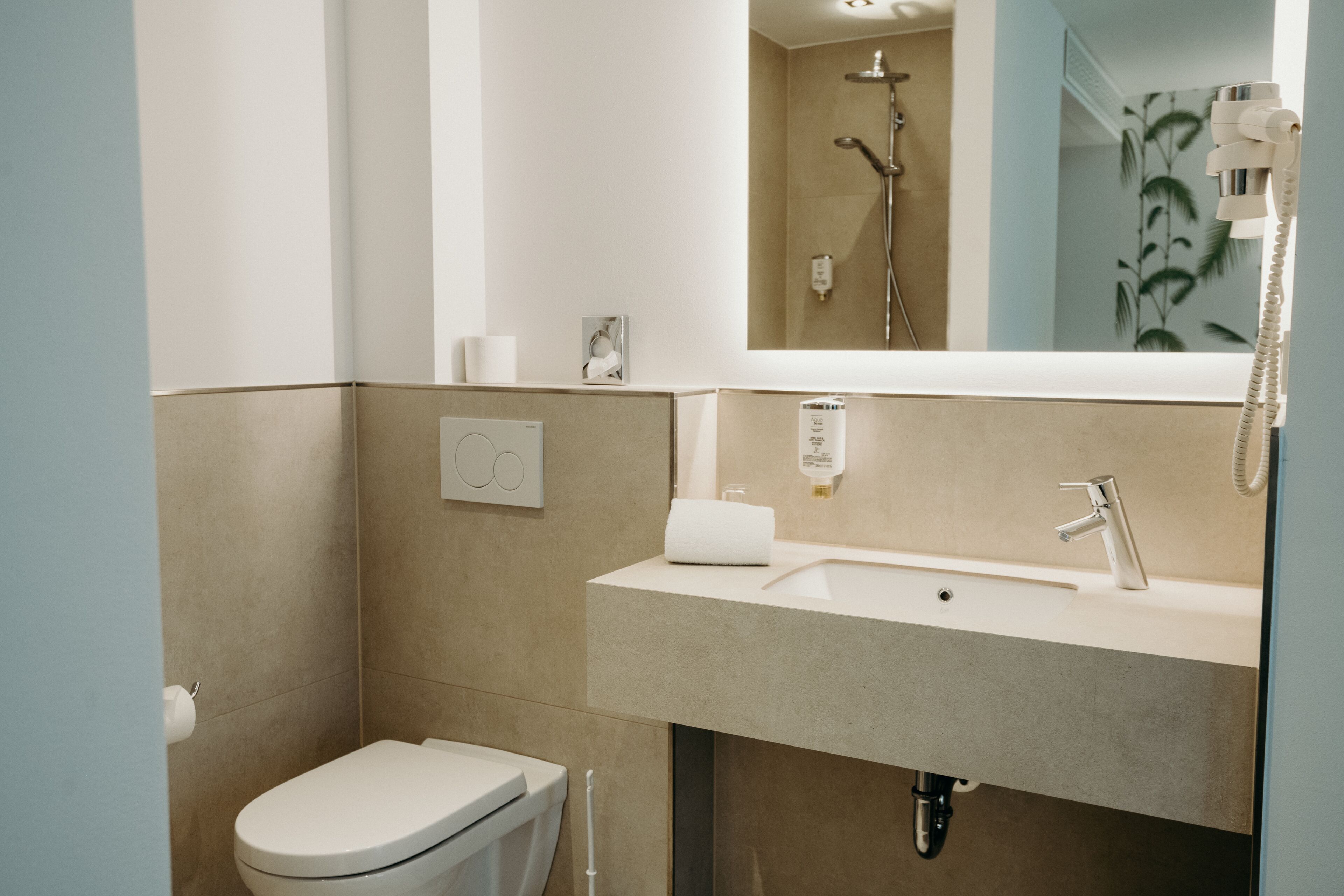 Une salle de bain moderne équipée de toilettes, d’un lavabo et d’une douche.