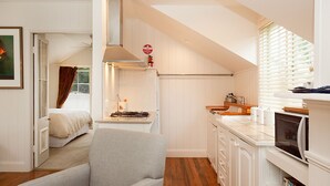 A compact kitchen with white cabinetry, a gas stove, and a window with blinds.