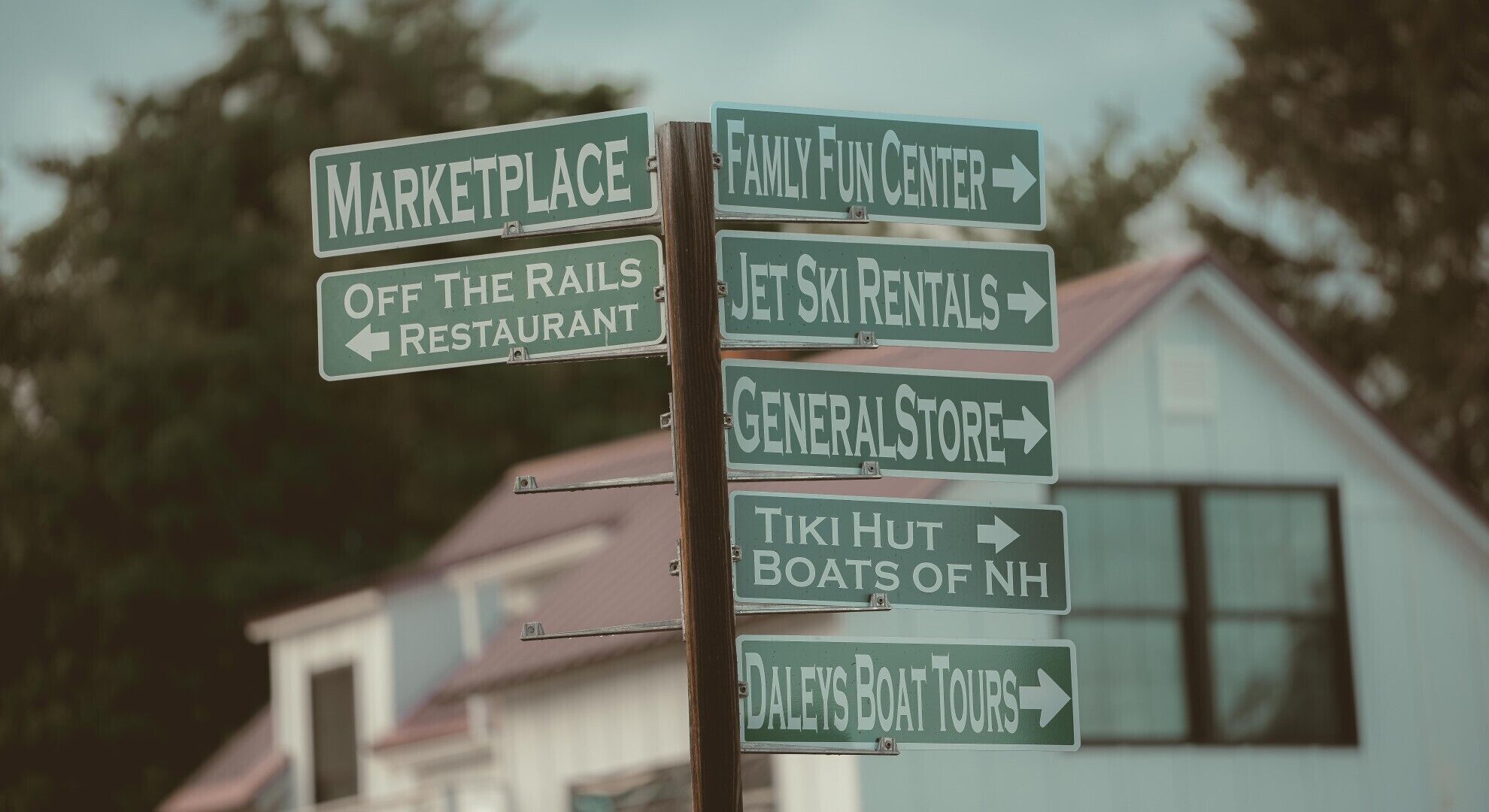 A directional signpost with multiple arrows pointing to various local attractions such as a marketplace, family fun center, and restaurant.