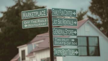 A directional signpost with multiple arrows pointing to various local attractions such as a marketplace, family fun center, and restaurant.