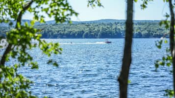 A lake with a boat in the distance and a forested hill in the background.