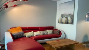 Ein modernes Wohnzimmer mit einem roten Sofa, einem Holztisch und einer Stehlampe.