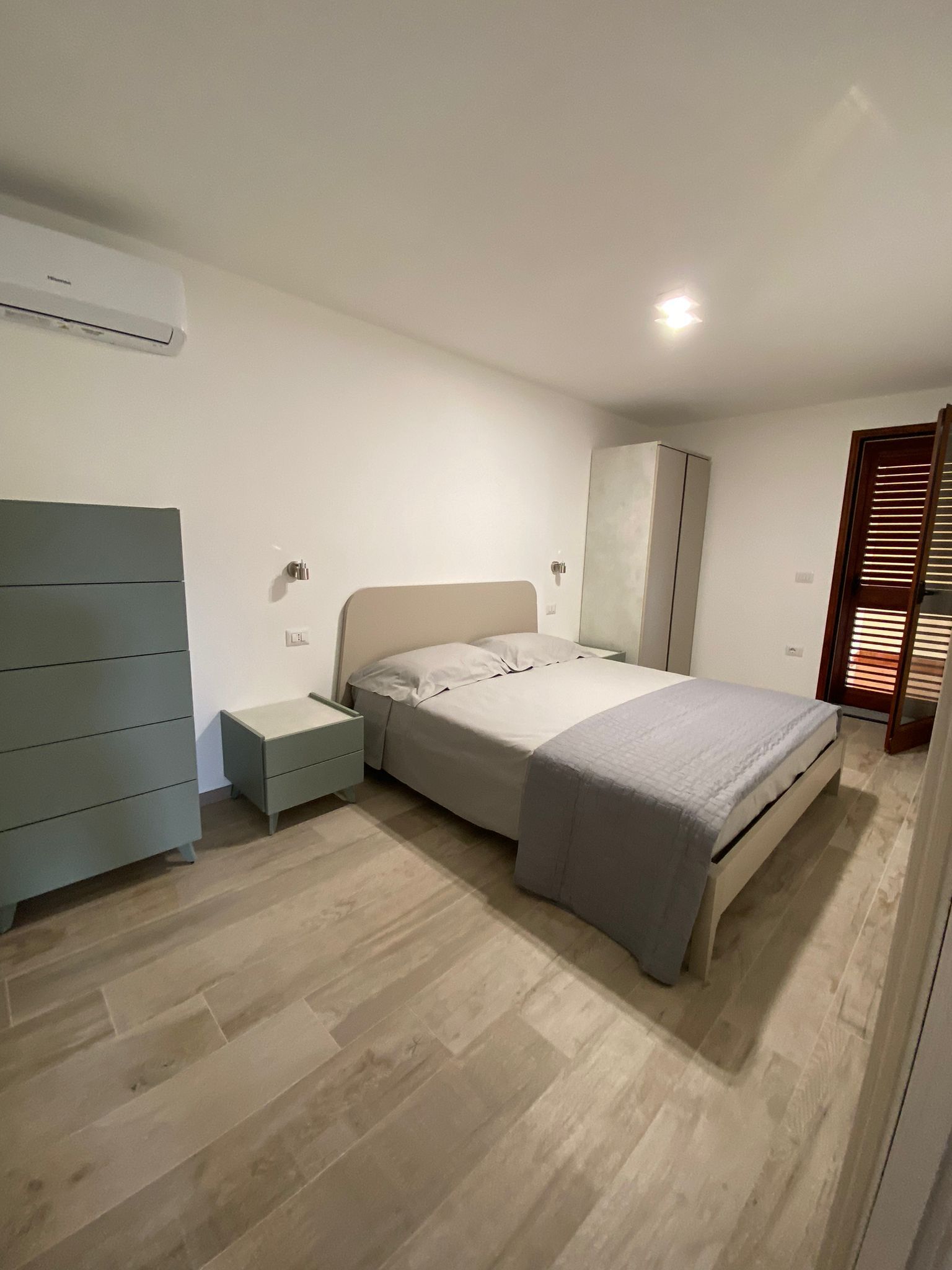 Un dormitorio con cama, armario, mesita de noche y un espejo de cuerpo entero.