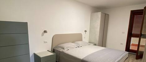 Un dormitorio con cama, armario, mesita de noche y un espejo de cuerpo entero.
