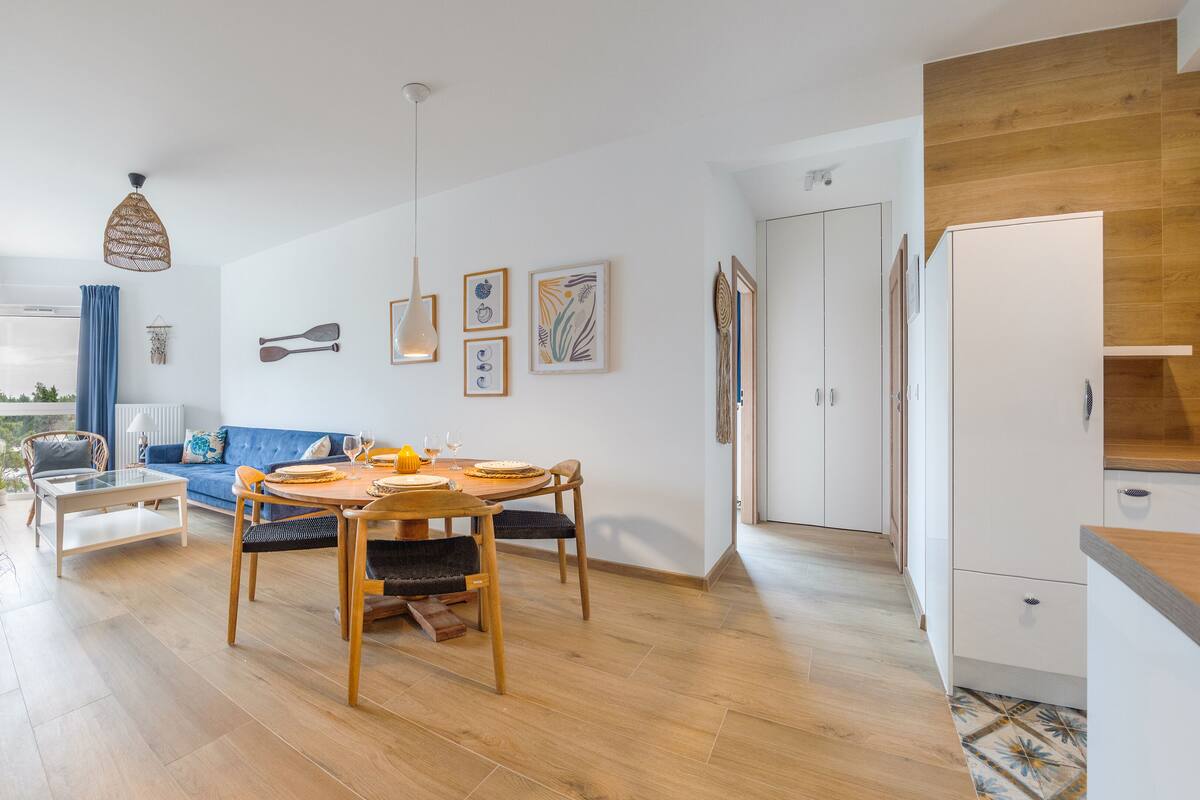 A modern living space with a dining area, a sofa, and a kitchen.
