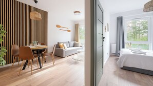 Quarto moderno com área de jantar, sofá e cama.
