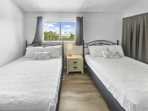 A room with two beds, a nightstand, and a window with curtains. - GULF FRONT/Renovated-2 Bikes- Private Beach Access (Santa Rosa Beach)