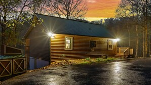 A wooden cabin with a metal roof, a front porch, and a garage. - Deer Browse Hideaway: Sink a Putt, Soak It In (Sevierville)