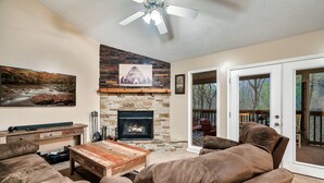 A cozy living room with a stone fireplace, leather sofas, and a large painting. - Deer Browse Hideaway: Sink a Putt, Soak It In (Sevierville)
