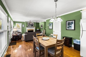 A dining area with a wooden table and chairs, a fireplace, and green walls.
