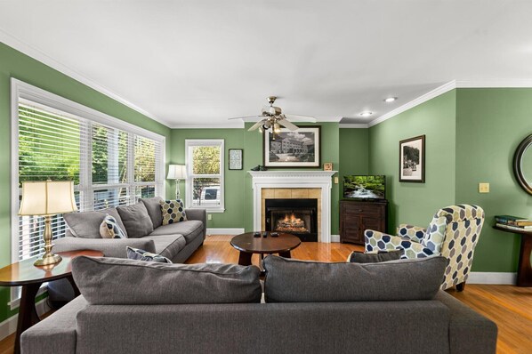 A living room with a fireplace, green walls, and a ceiling fan.