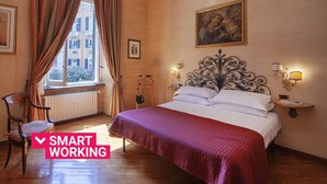 Ein Hotelzimmer mit einem Bett, einem Sessel, einem Fenster mit Vorhängen und Bildern an den Wänden.