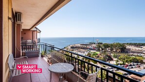 A balcony with a table and chairs, overlooking a coastal town and the sea. - Piazza Europa Landscape by Wonderful Italy (Catania)