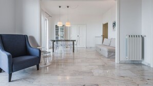 Un salon moderne avec un fauteuil bleu, une table à manger avec des chaises, un canapé blanc et un radiateur blanc.