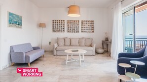 Un salon moderne avec un canapé, une table basse et un fauteuil bleu. Il y a un tableau au mur et une lampe.