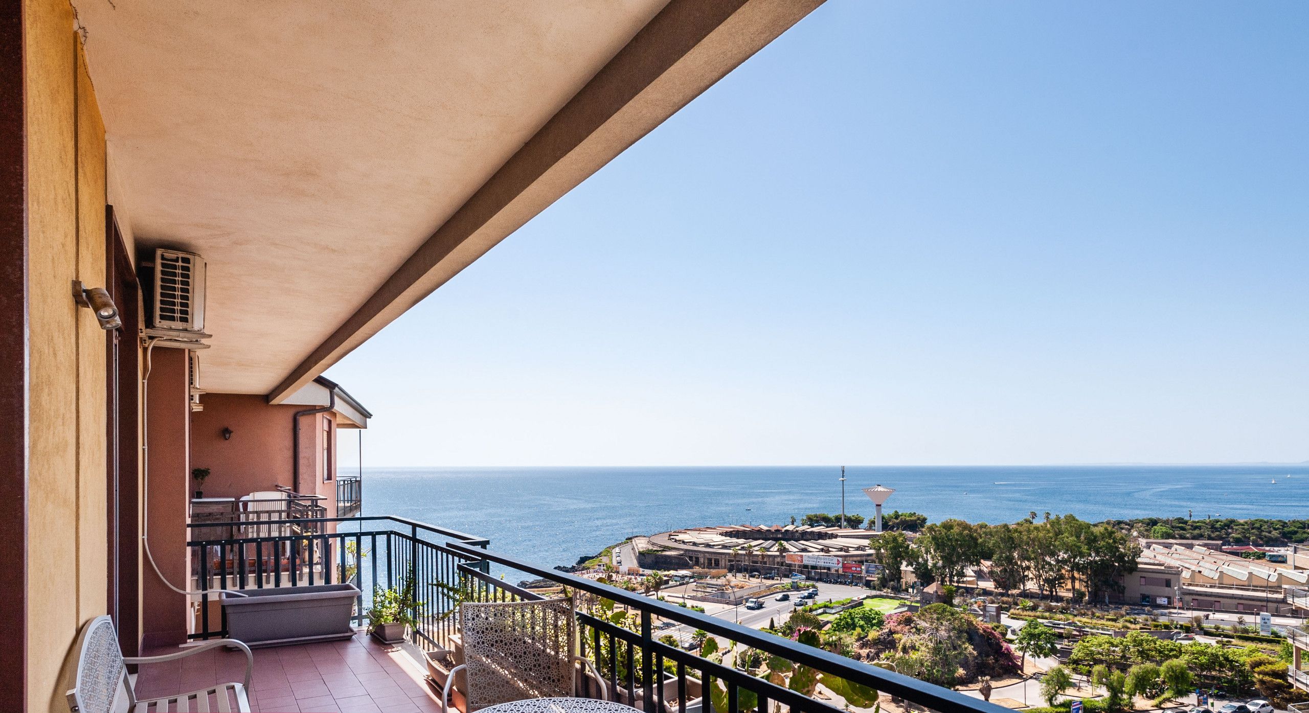 Un balcón con mesa y sillas, con vista a un pueblo costero y al mar.