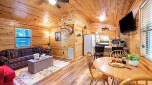 Un intérieur de chalet chaleureux comprenant un espace de vie, une table à manger et une cuisine.
