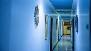 A hallway with blue walls, framed pictures, and a ceiling light. - Kelin Hotel & Suite (Lagos)