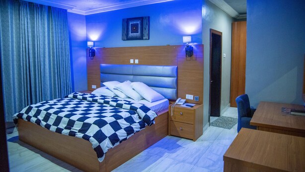 A hotel room with a large bed, bedside tables, a desk, and a chair. - Kelin Hotel & Suite (Lagos)
