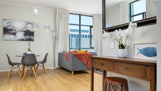 A modern living room with a dining area, a sofa, a coffee table, and a large window with curtains. - The Axis 212 (Cape Town)