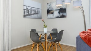 A dining area with a round table, four chairs, a potted plant, and two wall-mounted paintings. - The Axis 212 (Cape Town)
