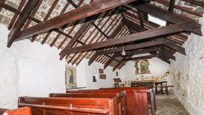 Ein Kircheninneres mit Holzbänken, Steinmauern und einer Holzbalkendecke.