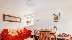 Ein Wohnzimmer mit einem roten Sofa, einem Holztisch und einem Essbereich mit einem Holztisch und Stühlen.