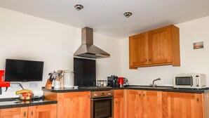 Eine moderne Küche mit Holzausstattung, einer Edelstahl-Dunstabzugshaube, einer Mikrowelle und einer Kaffeemaschine.