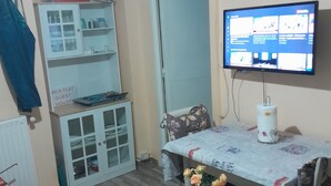 Ein gemütlicher Raum mit Esstisch, Fernseher und einem kleinen Schrank.