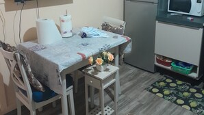 Eine kleine Küche mit Mikrowelle, Kühlschrank und einem Essbereich mit Tisch und Stühlen.