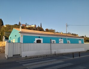 A building with a blue facade, white trim, and a tiled roof.