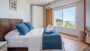 Ein Schlafzimmer mit Bett, Kleiderschrank, einem Fenster mit Aussicht und Fliesenboden.
