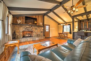 Cozy living room with a stone fireplace, leather sofa, and dining area.