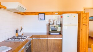 A compact kitchen with a gas stove, wooden cabinets, a microwave, and a refrigerator. - House for 6 - all on foot (Le Guilvinec)