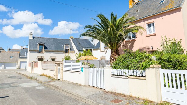 A residential street with houses, a white gate, and a palm tree. - House for 6 - all on foot (Le Guilvinec)