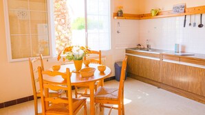 A kitchen with wooden cabinets, a sink, and a window with a view of greenery. - House for 6 - all on foot (Le Guilvinec)