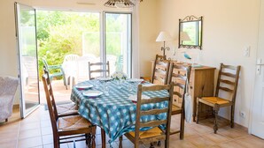 Comedor con una mesa preparada para cuatro personas, rodeado de sillas de madera, un armario de madera y una lámpara colgante.