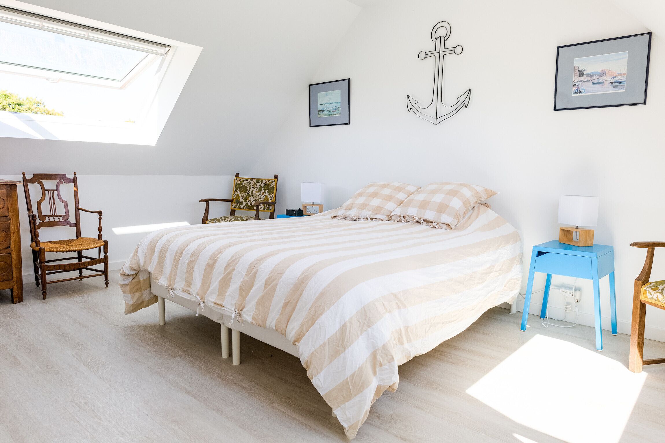 Une chambre à coucher avec un lit, deux chaises, une petite table et une fenêtre.