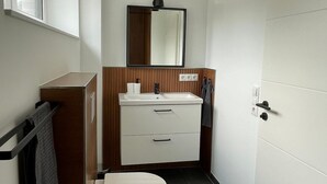 Een moderne badkamer met toilet, wastafel en spiegel.