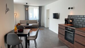 Een moderne keuken met een inbouwoven en een eethoek met een tafel en stoelen.